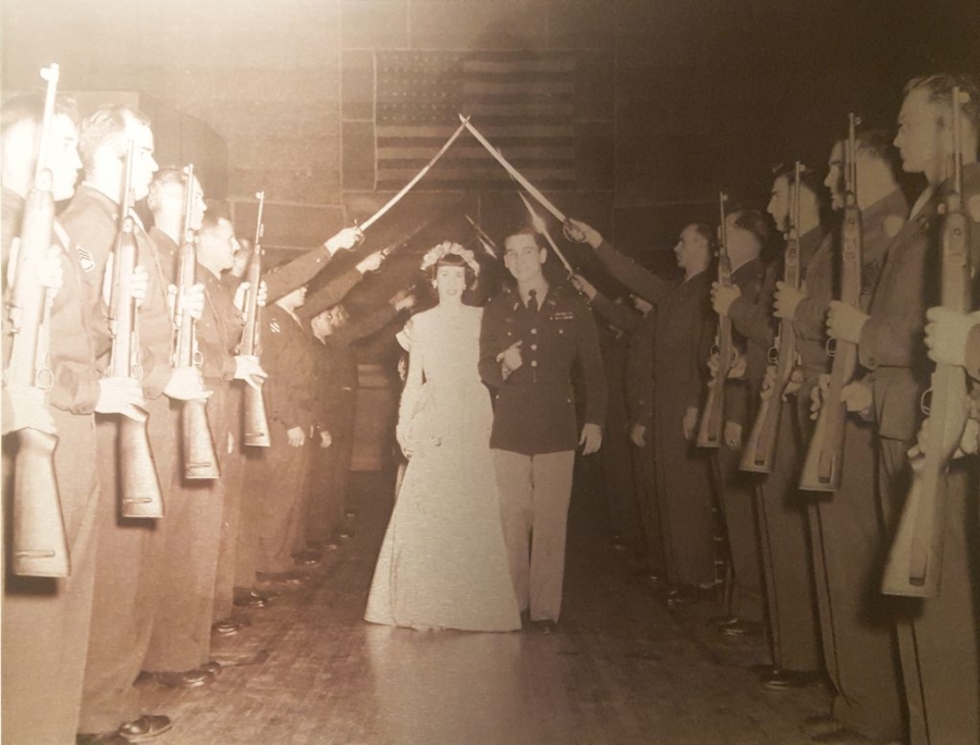 A married couple walks down an aisle of armed forces members at the Mashall Street Armory. 